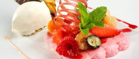 A dessert plate with a scoop of ice cream, a fruit arrangement, and a chocolate piece.