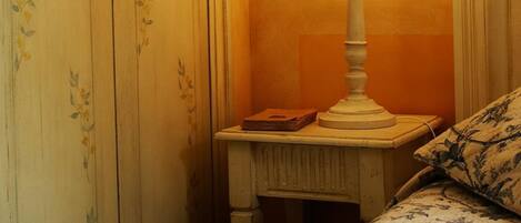 A bedroom with a bed, a nightstand, a lamp, and a wardrobe.