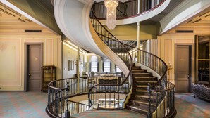 A grand spiral staircase with a chandelier, leading to a dining area with a round table and chairs. - Bosphorus Palace Hotel - Special Class (Istanbul)
