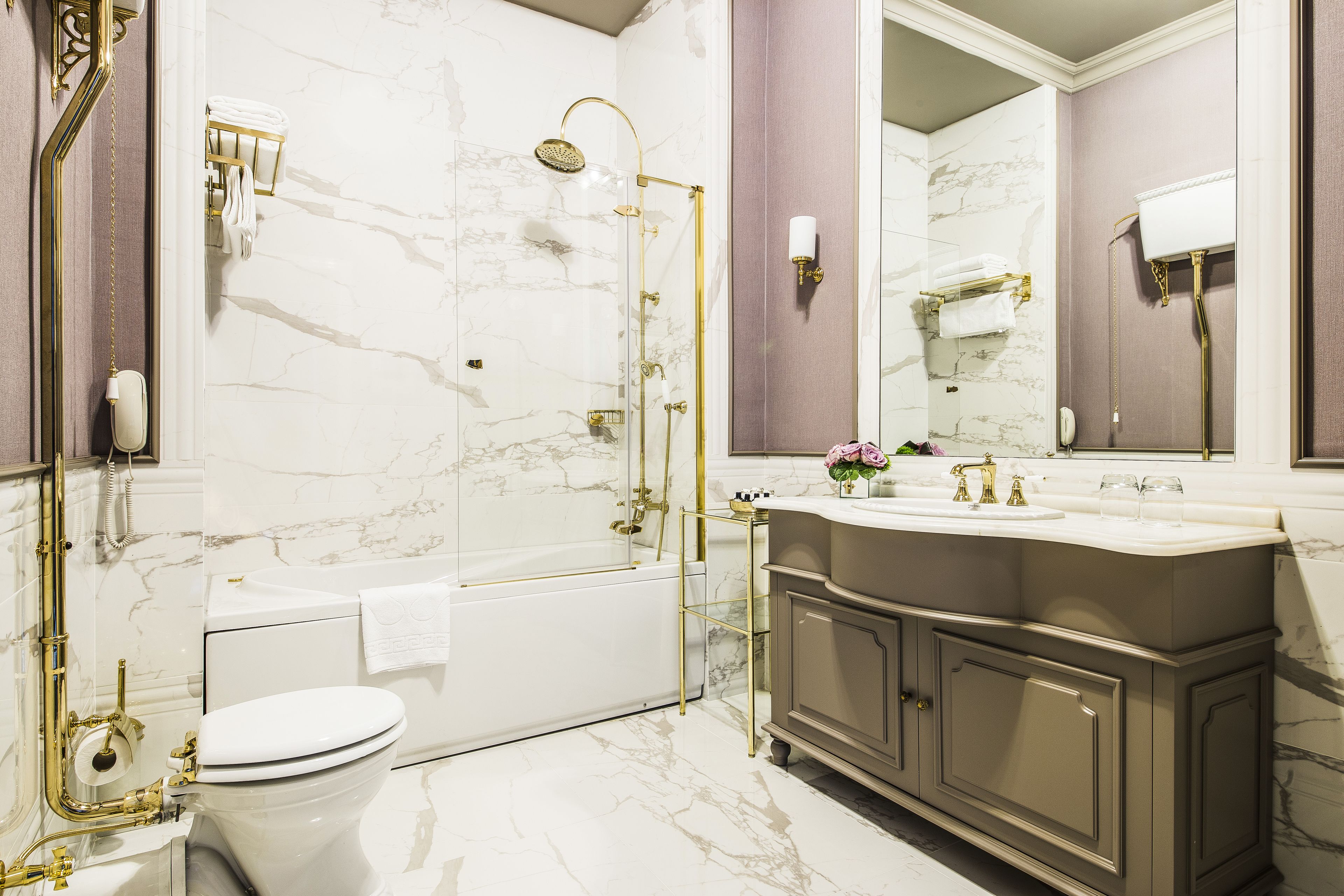 A luxurious bathroom with a marble floor, a bathtub, a toilet, and a vanity with a sink and mirror.