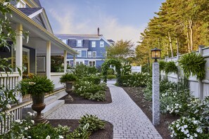 Stroll through the beautifully maintained garden, surrounded by a variety of plants and flowers, along a paved pathway.