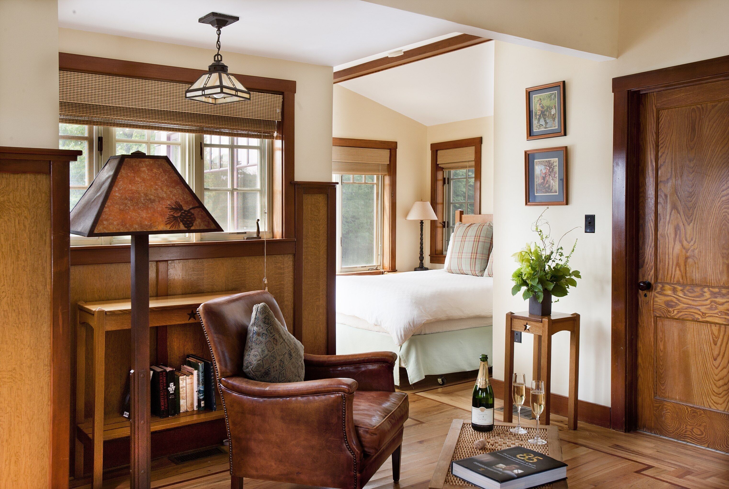 A cozy room with a wooden chair, a bookshelf, a bed with a white comforter, and a wooden door.