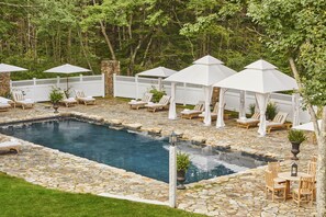 Relax by the serene pool surrounded by lush greenery and comfortable lounge chairs.