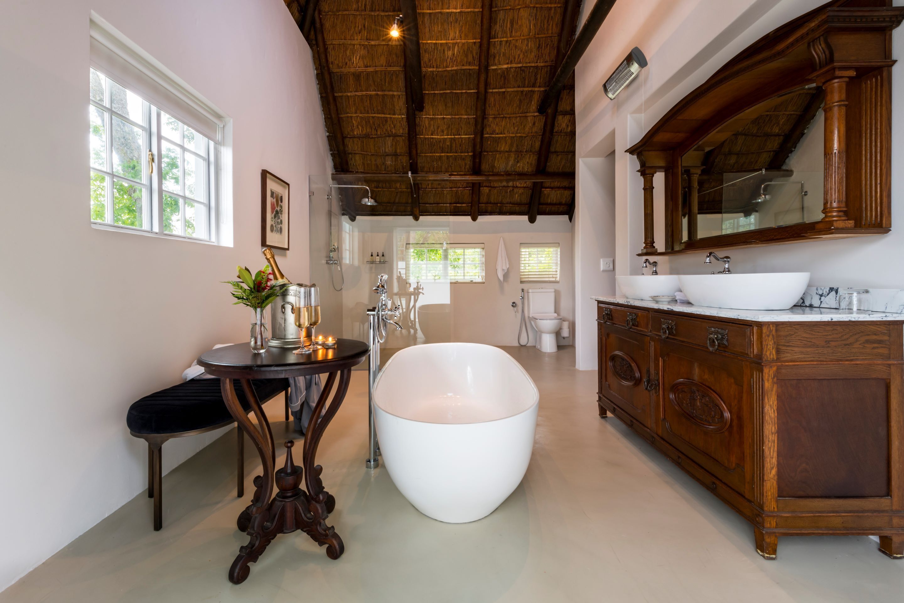 Une salle de bain dotée d’une grande baignoire, d’un meuble-lavabo en bois et d’une fenêtre donnant sur un paysage verdoyant.
