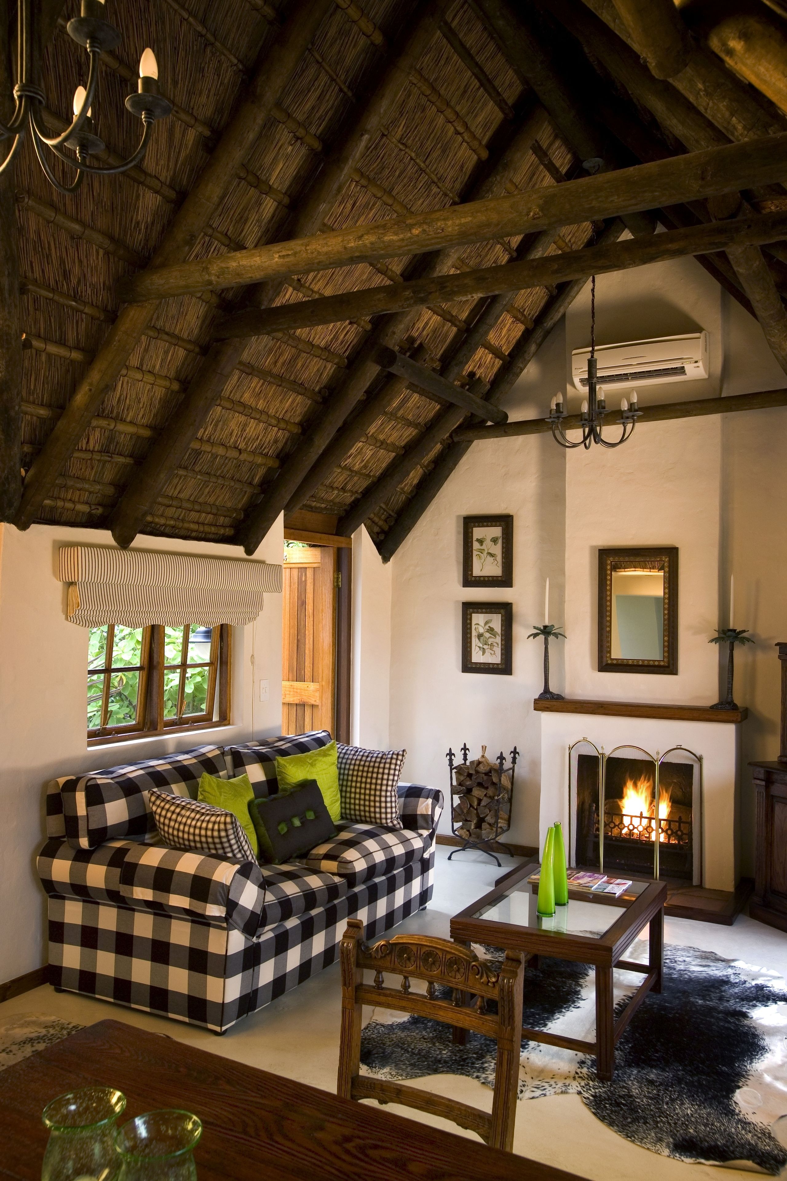 A cozy living room with a checkered sofa, a fireplace, and a chandelier.