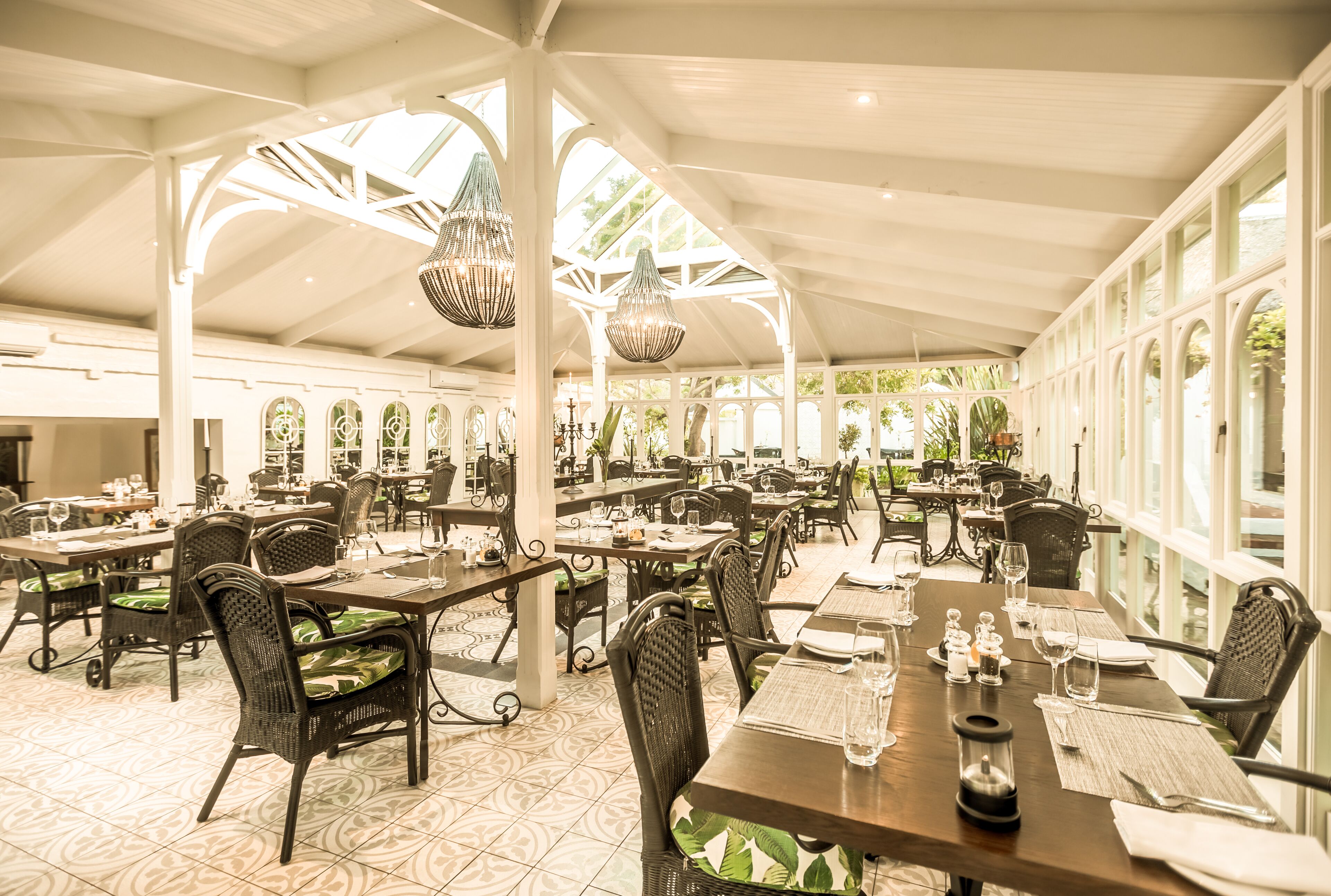 Un vaste espace de restauration intérieur, doté de nombreuses tables et chaises, de grandes fenêtres et de luminaires suspendus.