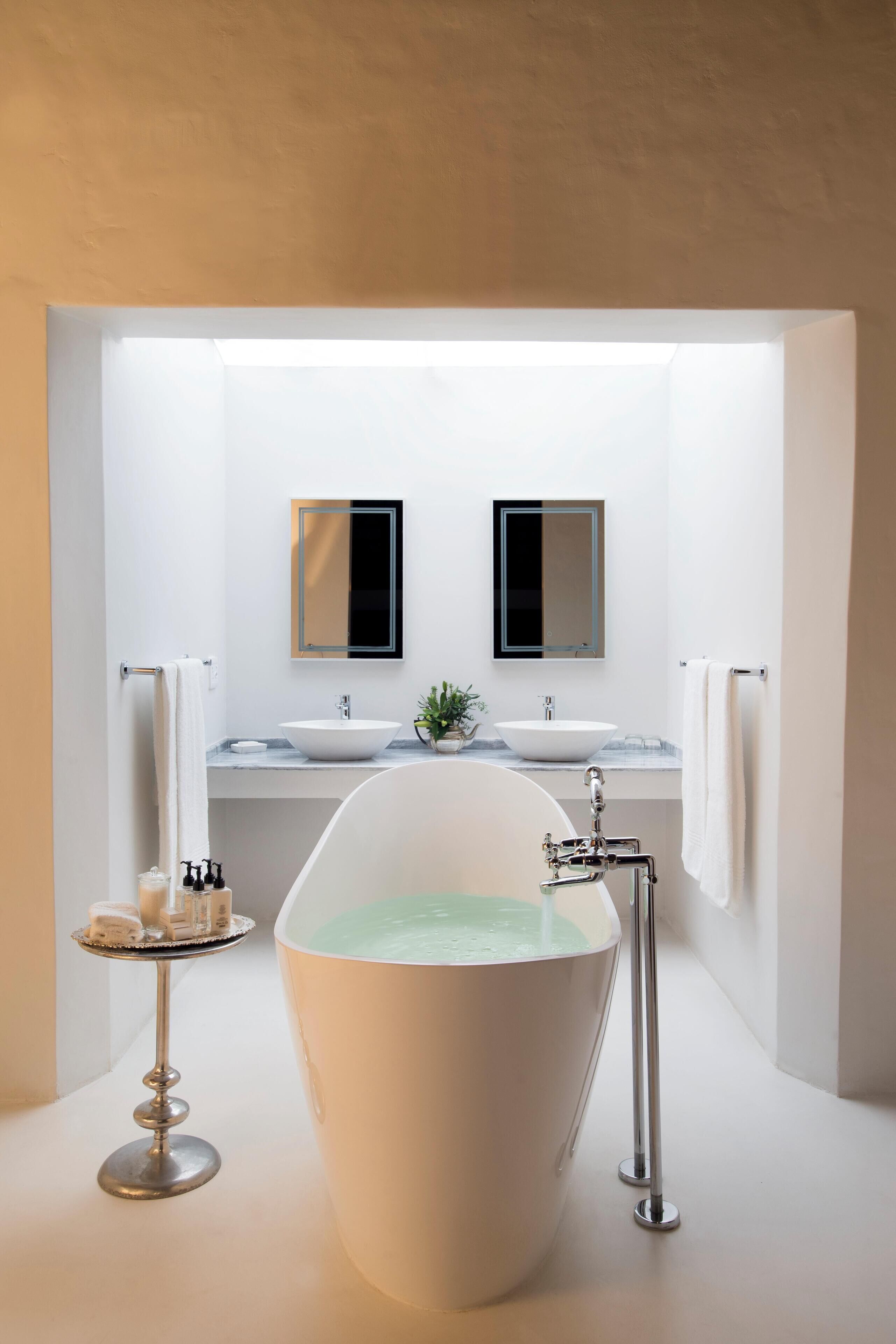 A modern bathroom with a freestanding bathtub, two sinks, and a large mirror above each sink.