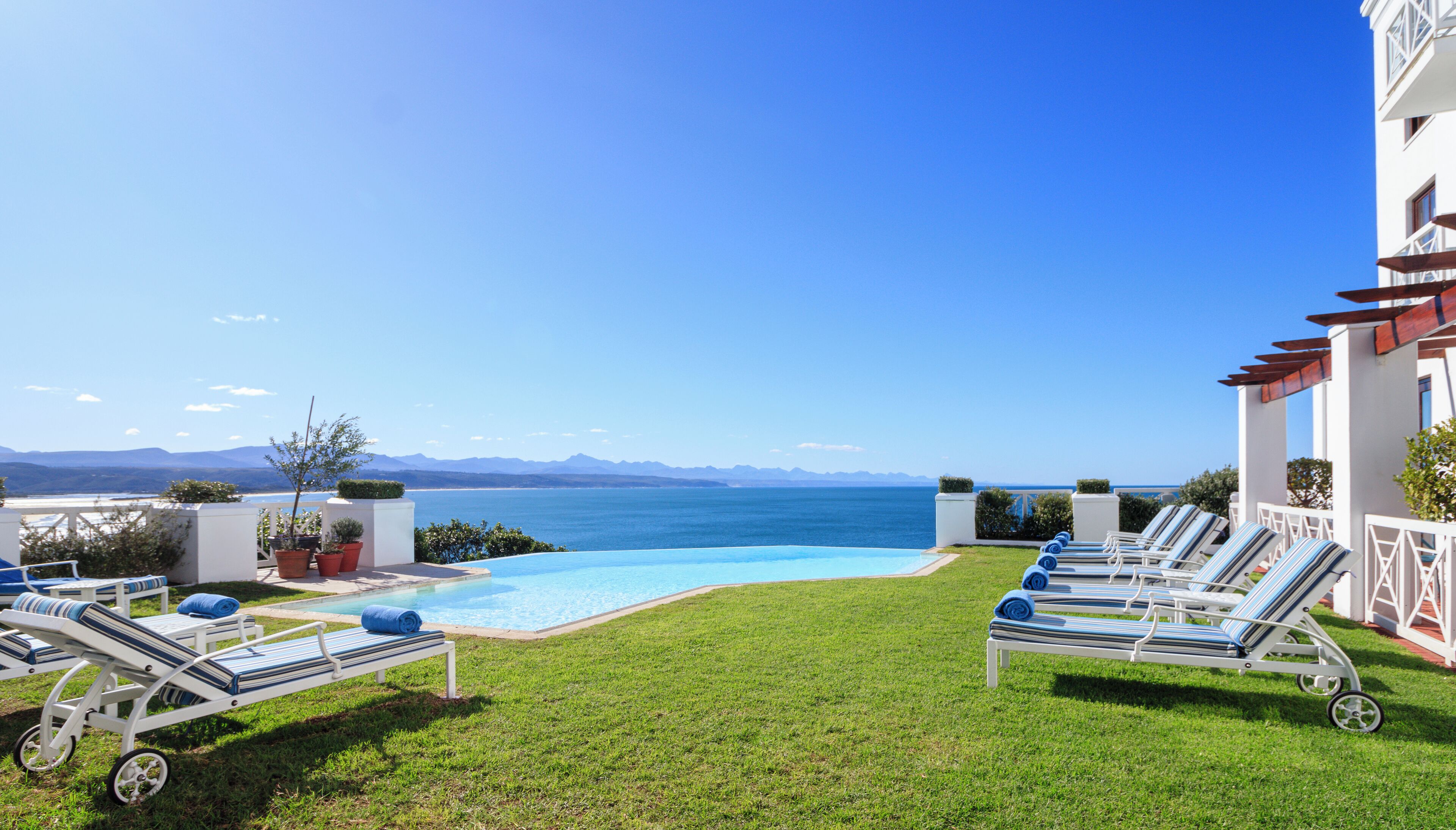 A poolside area with lounge chairs and a view of the sea.