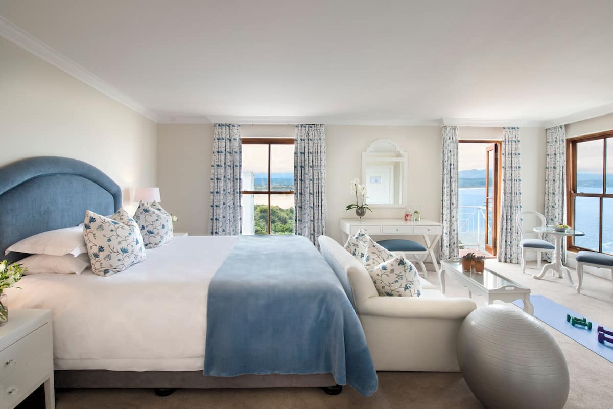 Une chambre à coucher avec un lit, un bureau, une chaise, une télévision et une vue sur la mer.