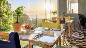 A dining area with tables set for two, potted plants, and a view of the sea. - The Plettenberg Hotel (Plettenberg Bay)
