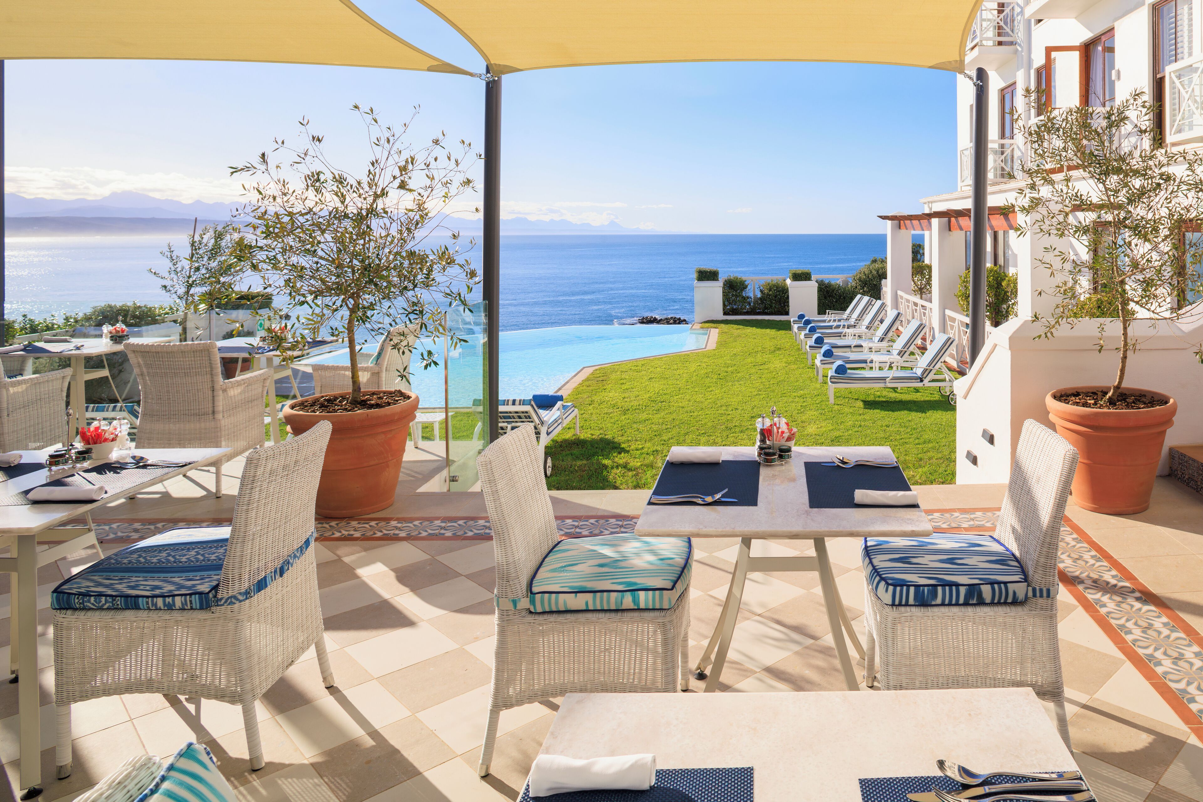 A terrace with wicker furniture, a pool, and a view of the sea.