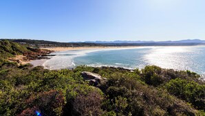 A coastal landscape with a beach, rocky outcrops, and dense vegetation. - The Plettenberg Hotel (Plettenberg Bay)