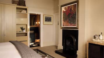 A bedroom with a bed, a fireplace, a bookshelf, and a framed artwork on the wall.