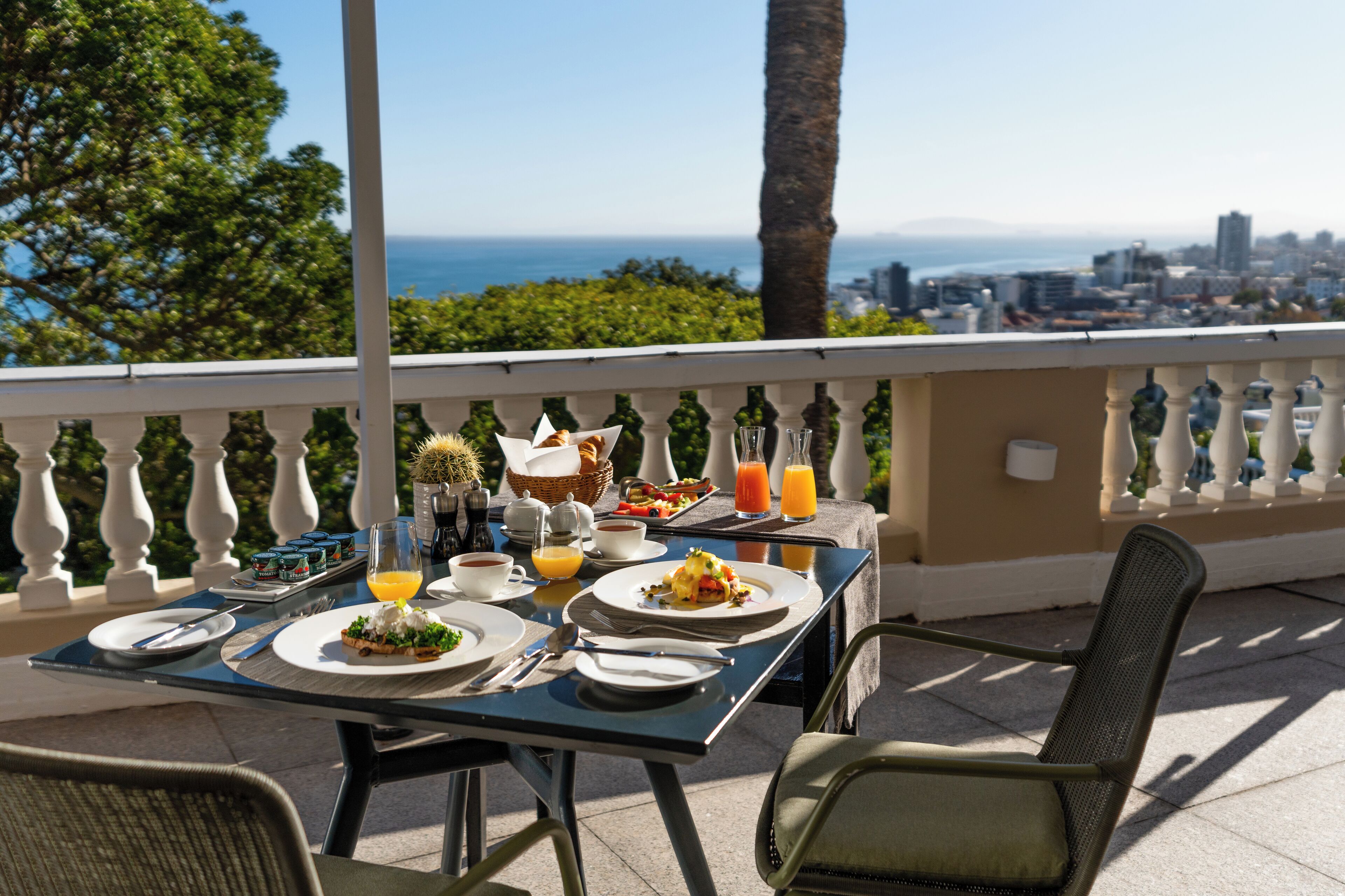 A table set for breakfast with a view of the city and ocean.