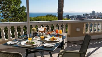 A table set for breakfast with a view of the city and ocean.