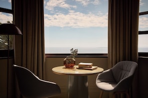 A room with a round table, two chairs, a vase with flowers, and a book.