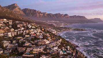 A coastal residential area with houses along the shoreline, a prominent mountain in the background, and a view of the ocean.