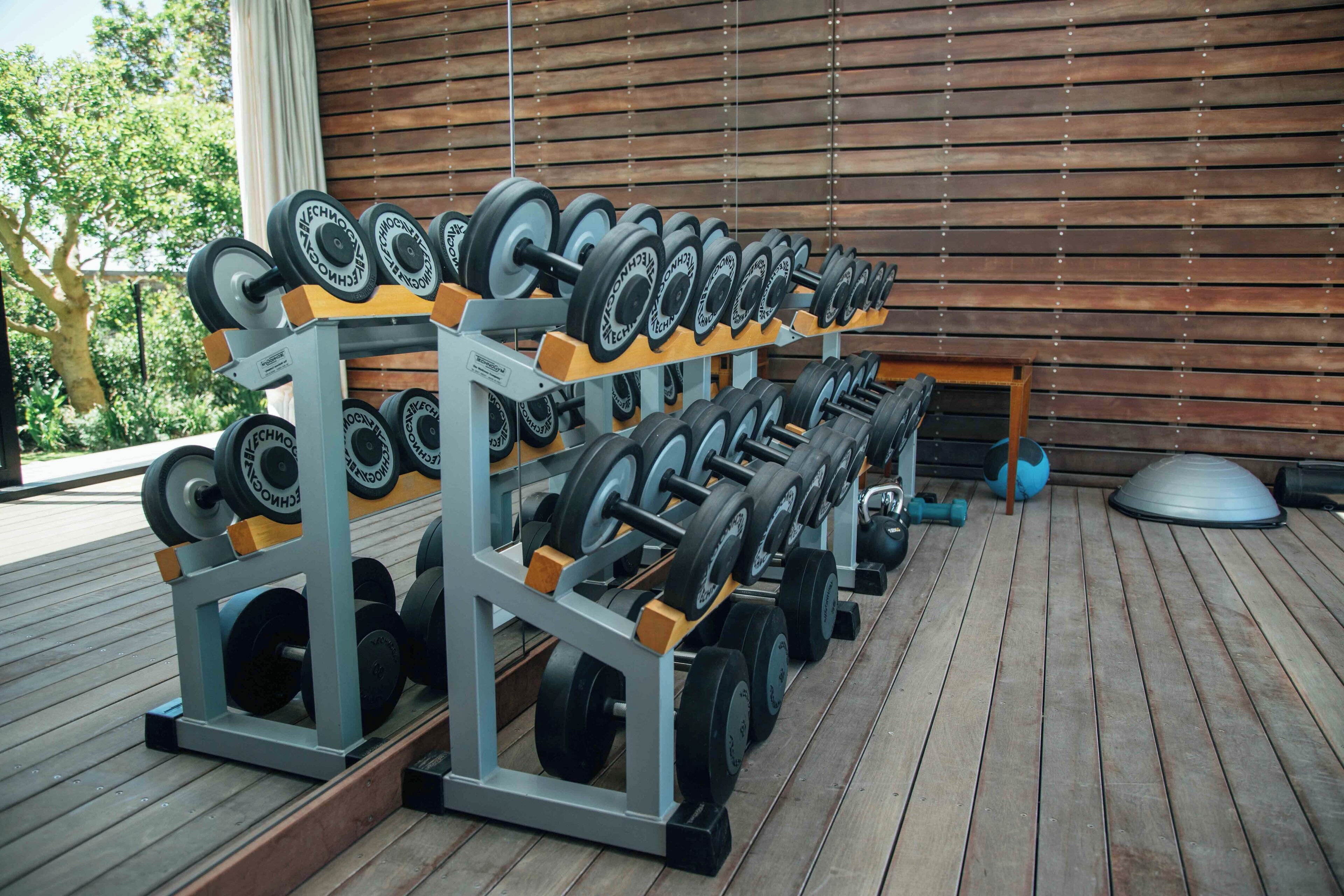 A gym with weightlifting equipment, including dumbbells and barbells, arranged on racks.