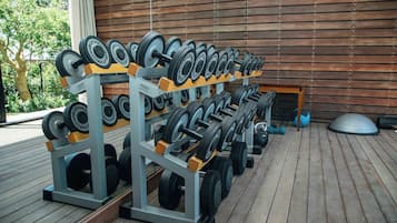 A gym with weightlifting equipment, including dumbbells and barbells, arranged on racks.