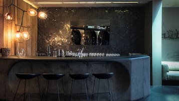 Ein moderner Barbereich mit rustikaler Steinwand, Barhocker und einer Weinschlange.