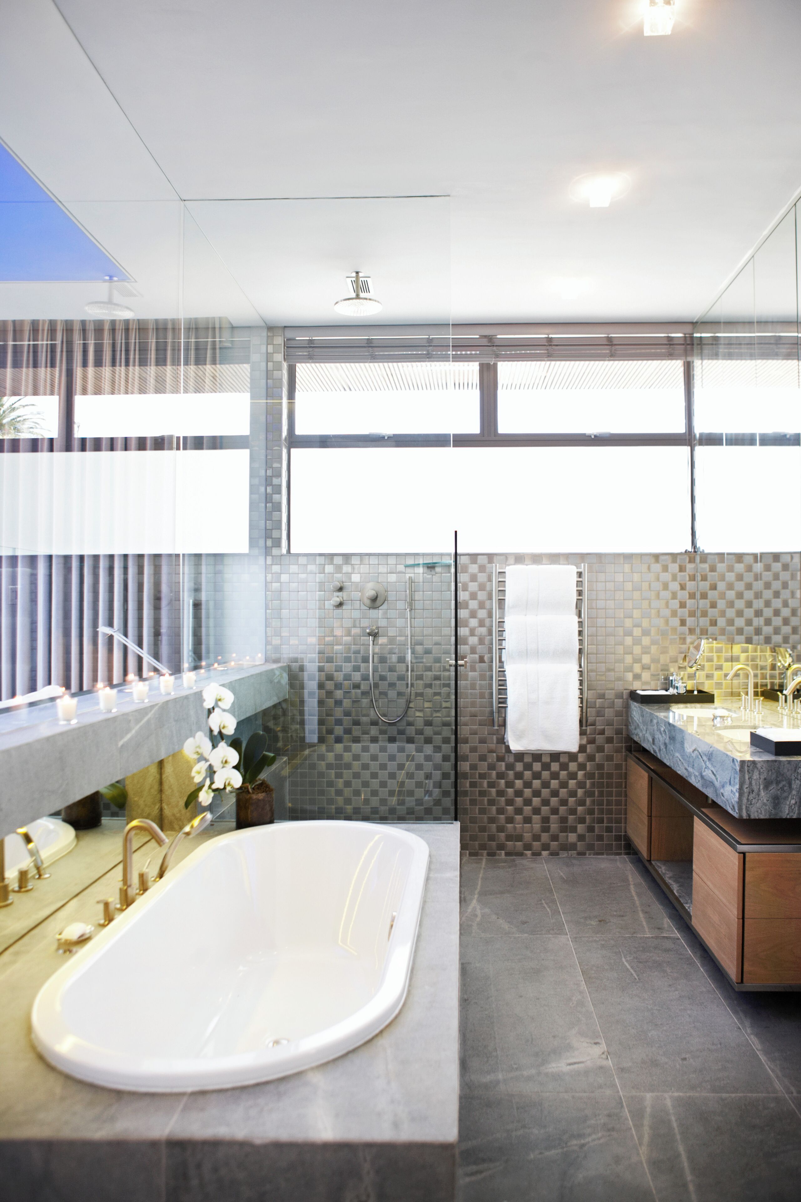A modern bathroom with a freestanding bathtub, a glass-enclosed shower, and a vanity with a large mirror.