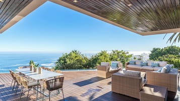 A wooden deck with outdoor furniture, overlooking a scenic ocean view.