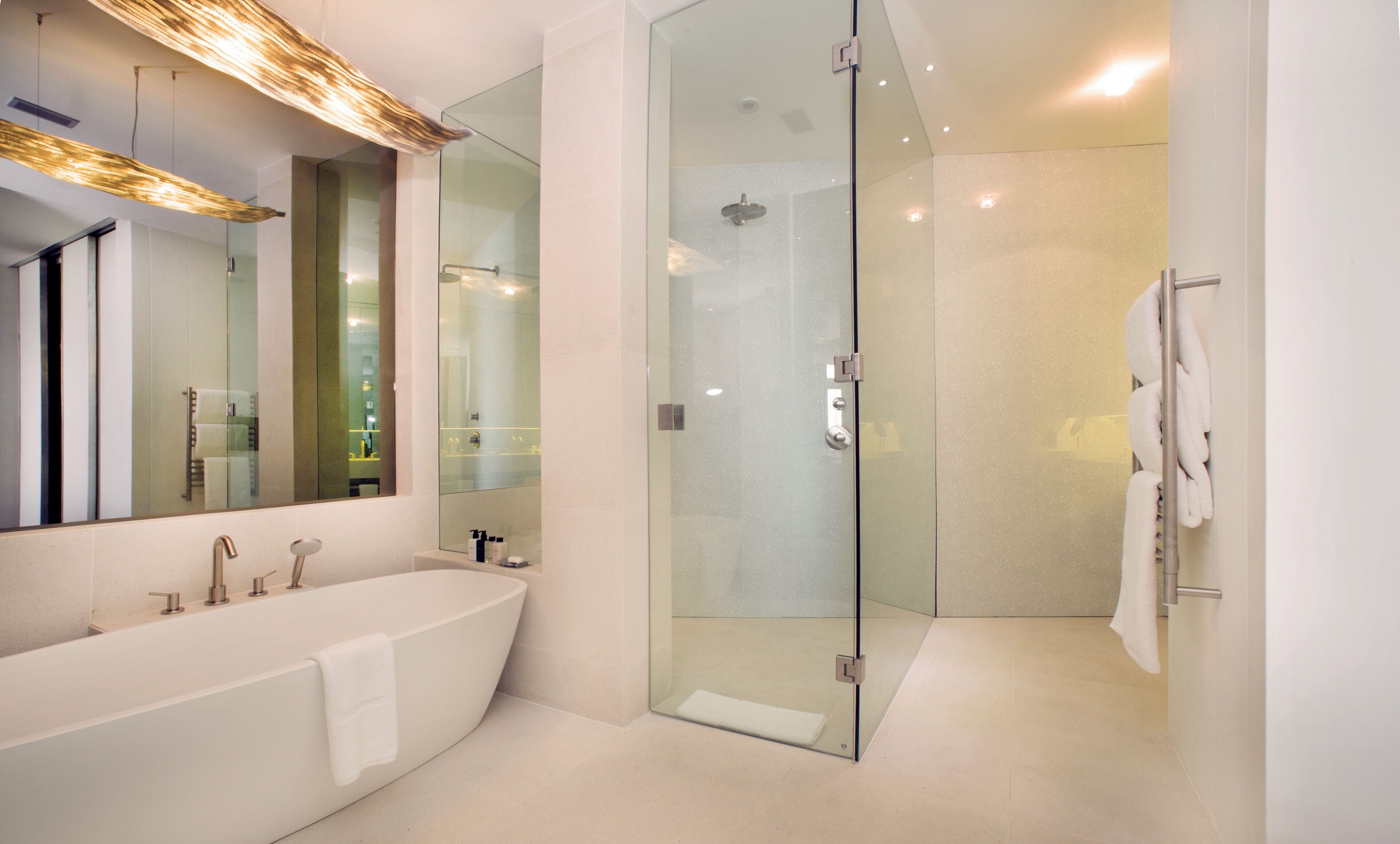 A modern bathroom with a glass-enclosed shower, a freestanding bathtub, and a large mirror.