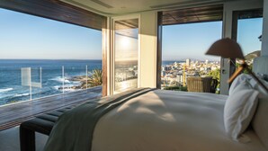 A bedroom with a large window overlooking a city and the ocean. - Ellerman House (Cape Town)