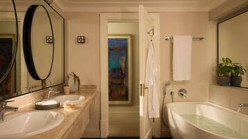 A bathroom with two sinks, a bathtub, a mirror, and a painting in the background.