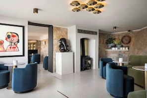 A modern lounge area with blue upholstered chairs, a stone accent wall, and a black sculpture.
