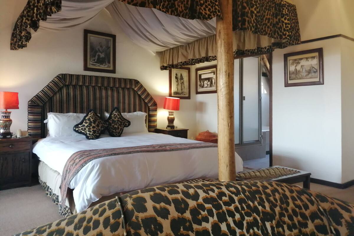 A bedroom with a canopy bed, leopard print bedding, and a mirror.