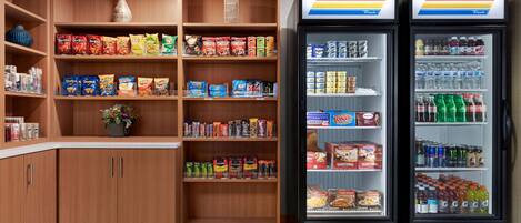 A snack and beverage kiosk with shelves stocked with chips, snacks, and bottled drinks.