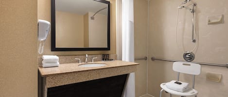 Un baño con lavamanos, espejo, toallero y ducha con cabezal de ducha de mano.