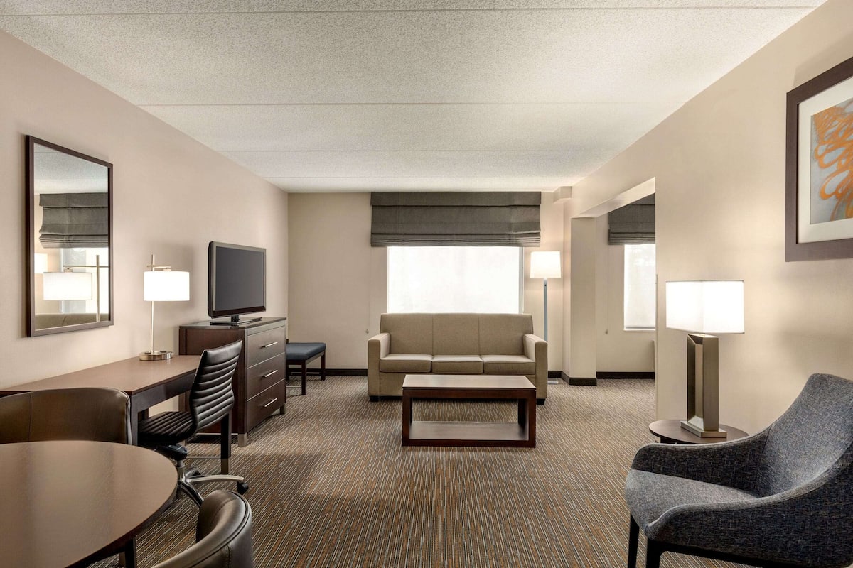 A hotel room with a sofa, a television, a desk, a chair, and a coffee table.