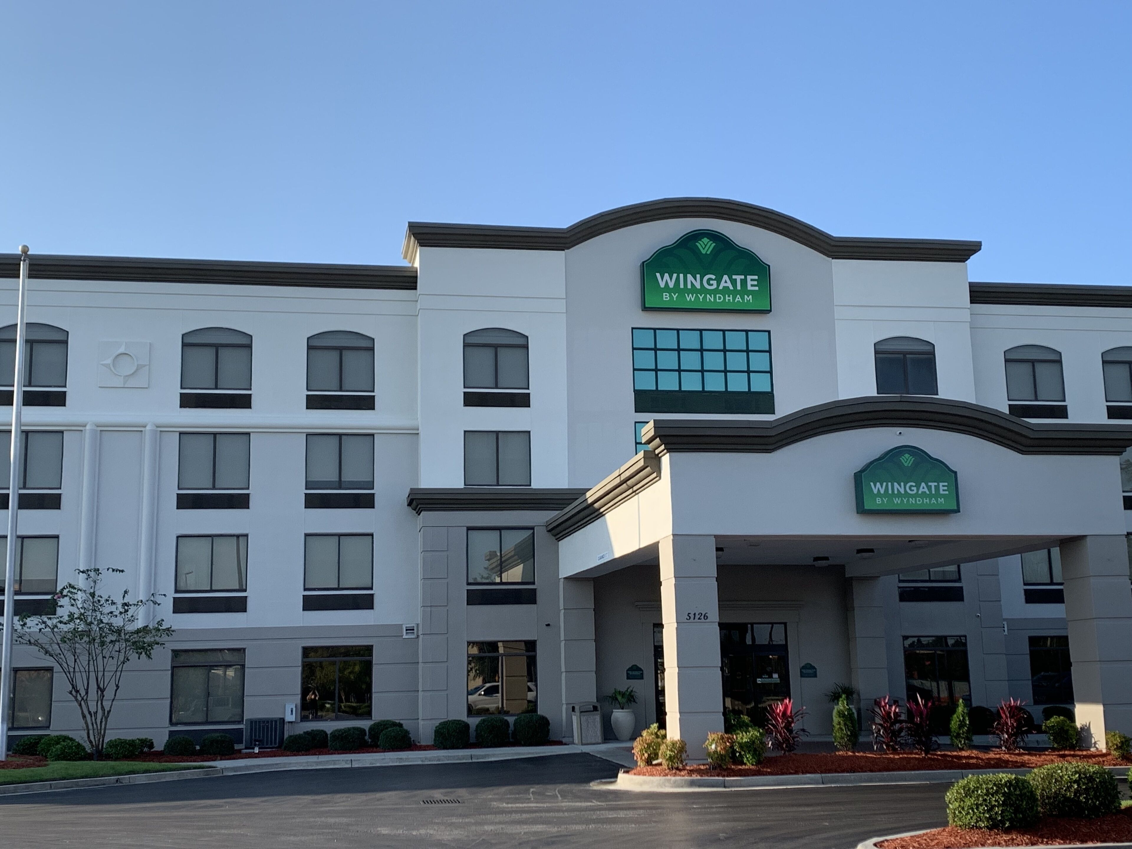 A multi-story hotel with a prominent green and white sign reading "Wingate by Wyndham".