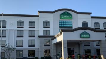 A multi-story hotel with a prominent green and white sign reading "Wingate by Wyndham".
