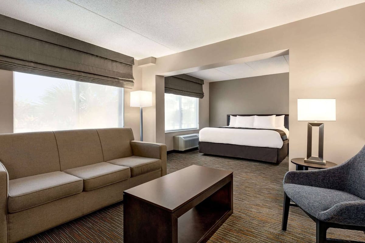 A hotel room with a sofa, a bed, a desk, and a chair.
