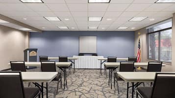 Sala de conferências com um púlpito, mesas, cadeiras e a bandeira americana.