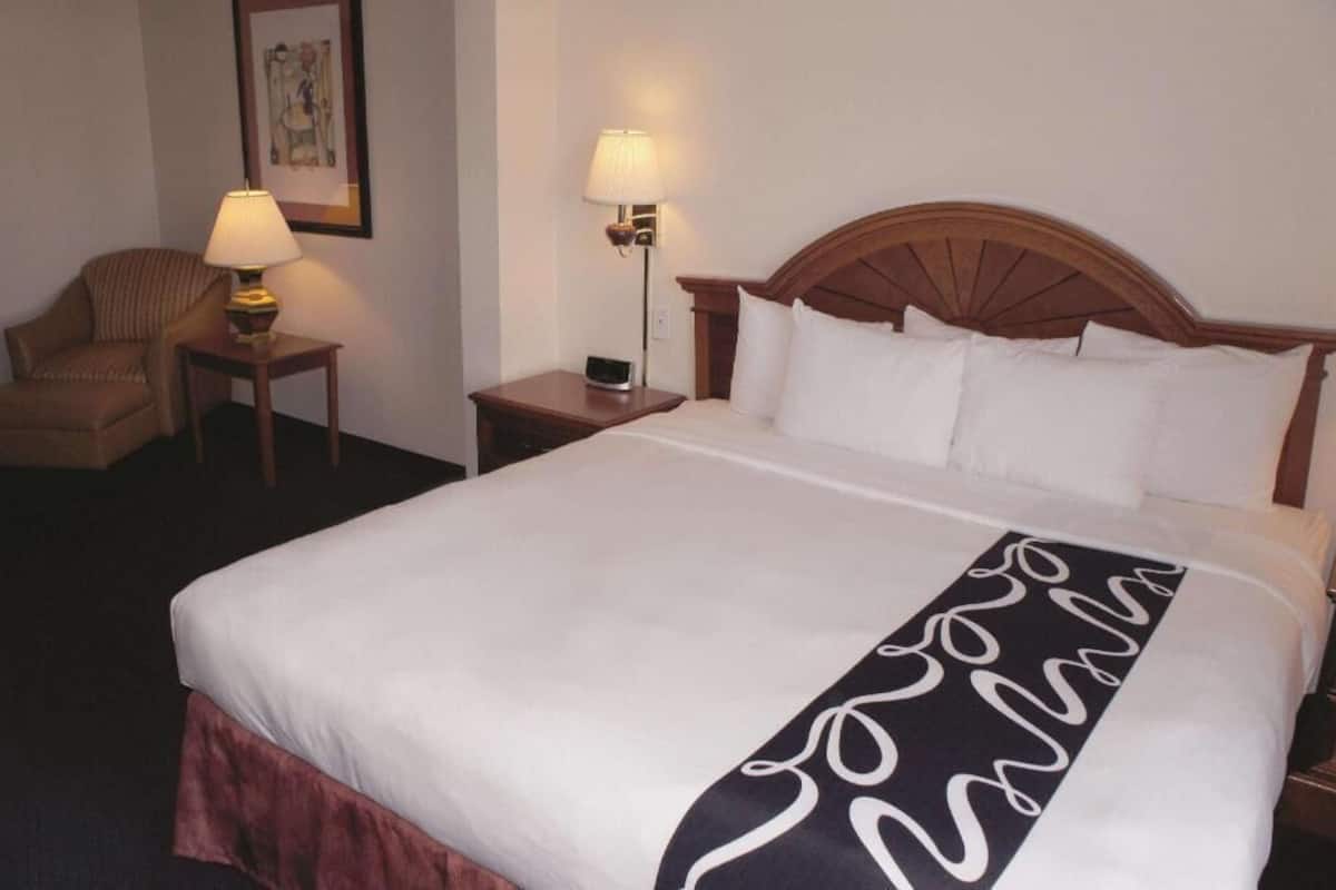 Hotellihuone, jossa on suuri sänky, kaksi yöpöytää valaisimineen, tuoli ja seinällä oleva kehystetty taulu.