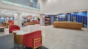 A spacious lobby with a reception desk, seating area, and a staircase leading to an upper level. - Hampton Inn by Hilton Addison Dallas (Addison)