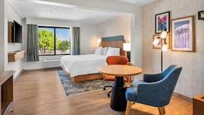 A hotel room with a bed, a desk, a chair, a TV, and a window with curtains. - Hampton Inn by Hilton Addison Dallas (Addison)