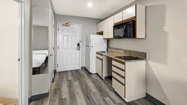 Cocina compacta con refrigerador, microondas y encimera de granito.