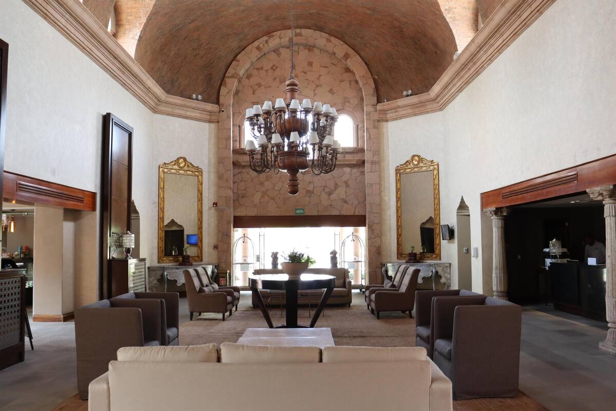 A lobby with a chandelier, seating, a reception desk, and a large mirror.