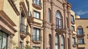 A historic building with multiple balconies and arched windows, surrounded by a reflective water feature and tropical plants. - Hilton San Luis Potosi (San Luis Potosi)