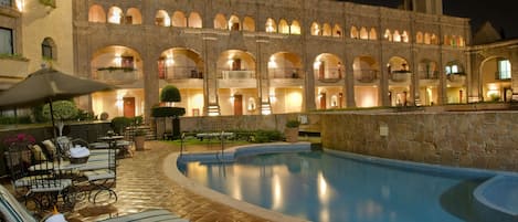 Una piscina al aire libre, sillones reclinables de piscina