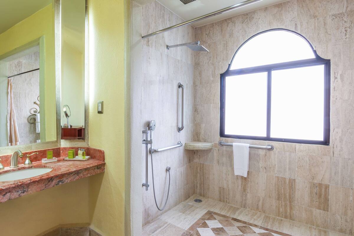 A bathroom with a shower, a sink, and a window.