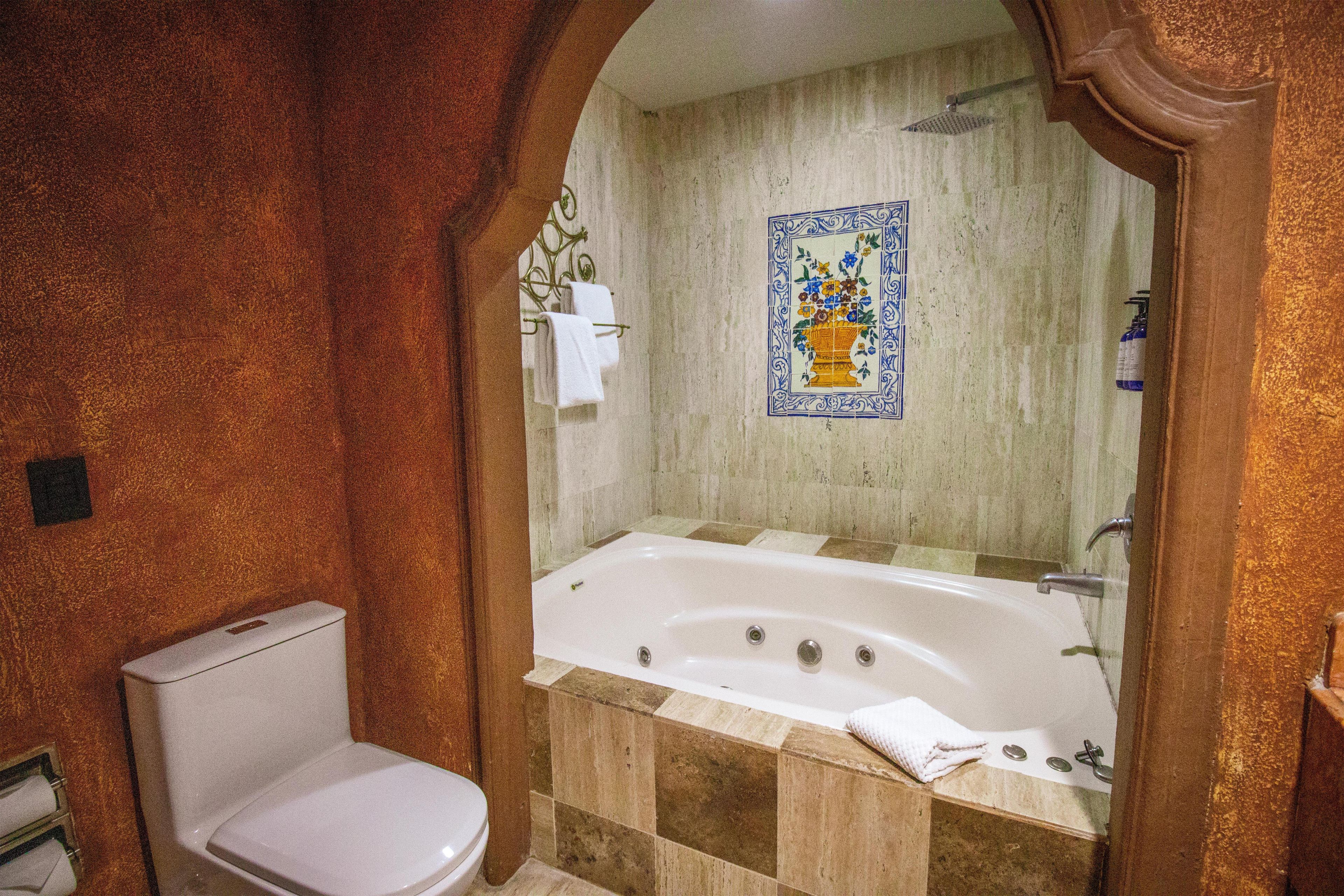 Un baño con bañera, inodoro y zona de ducha.