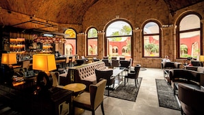 A spacious lobby with a bar area, comfortable seating, and large arched windows offering views of the exterior. - Hilton San Luis Potosi (San Luis Potosi)