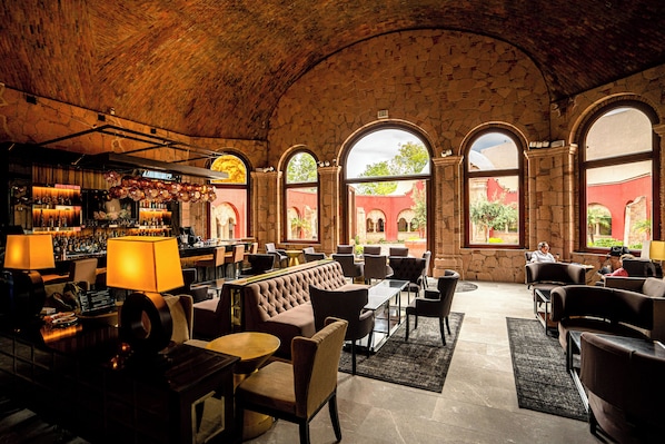 Un vestíbulo amplio con zona de bar, asientos cómodos y grandes ventanales con vistas al exterior.