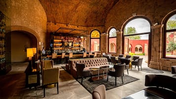 Área de bar com assentos e tela de televisão.